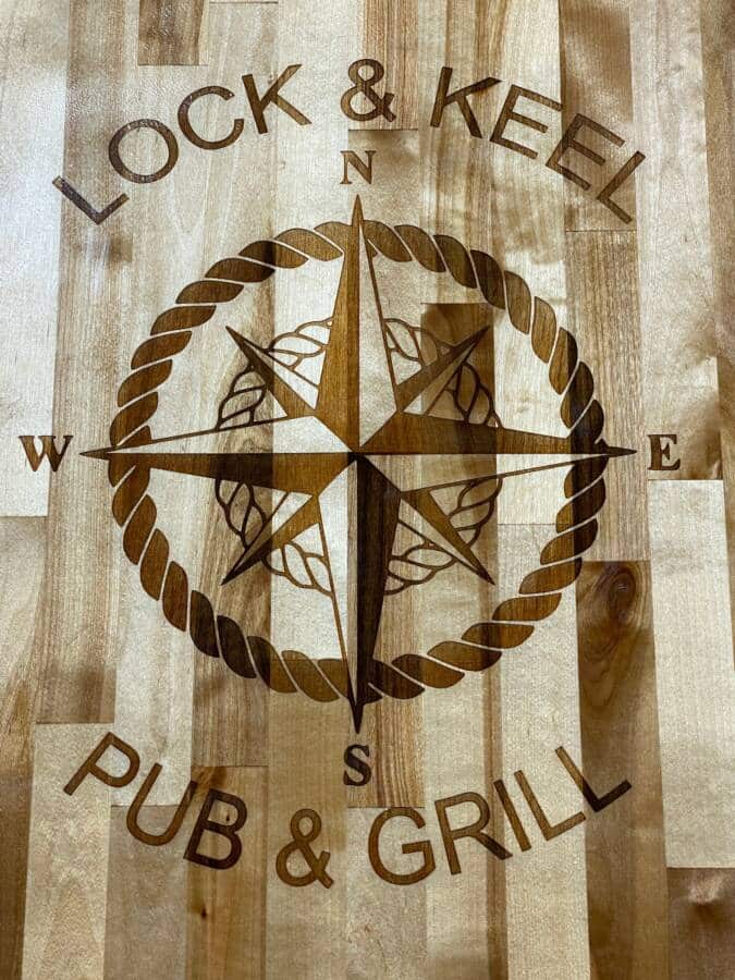Lock & Keel Pub & Grill with compass design on wooden surface.