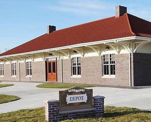 Historic train depot building with brick exterior and distinctive red roof.