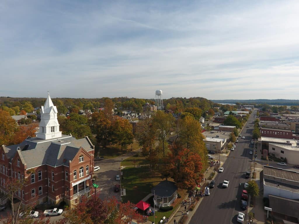 Aerial view of a historic Tell City, Indiana with colorful autumn trees and bustling streets.