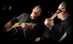 Live music performance featuring joyful musicians playing guitar on stage.