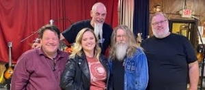 Group of musicians smiling together in a vibrant music venue.