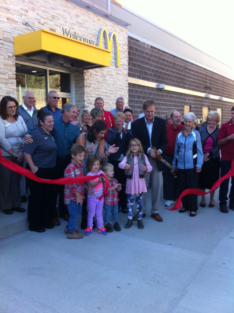 Celebrating the grand opening of a new McDonalds restaurant with a ribbon-cutting ceremony.