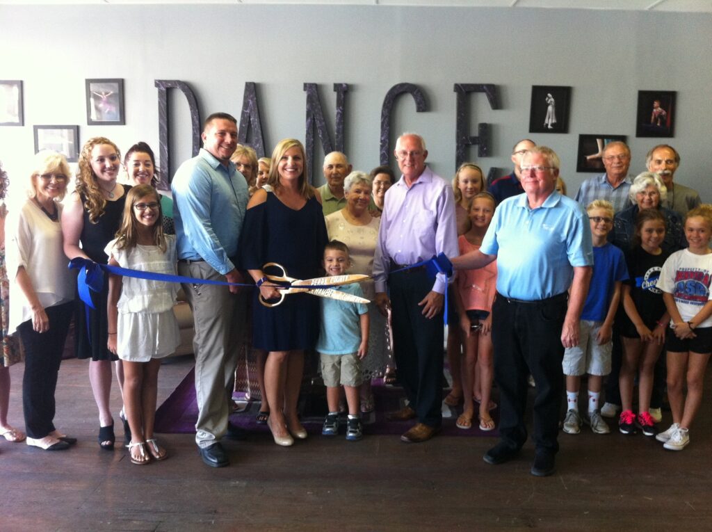 Grand opening celebration at a new dance studio with community members and a ribbon cutting.