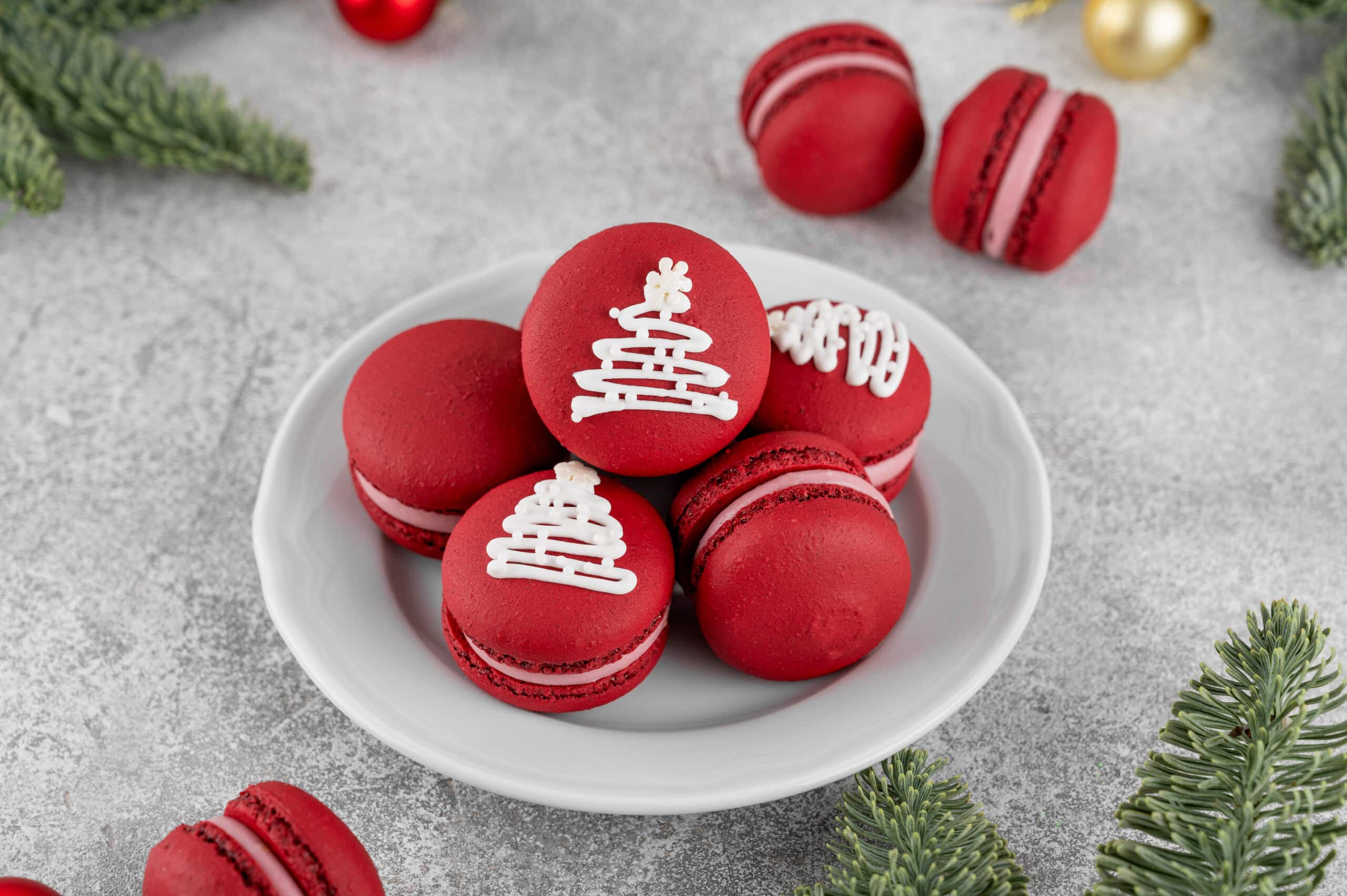 Festive red raspberry macaroons with sugar glaze on a white plate for Christmas.