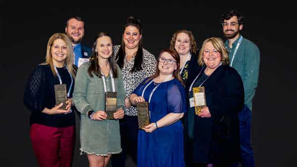 Winners celebrate at the 2023 awards ceremony with their trophies and joyful expressions.