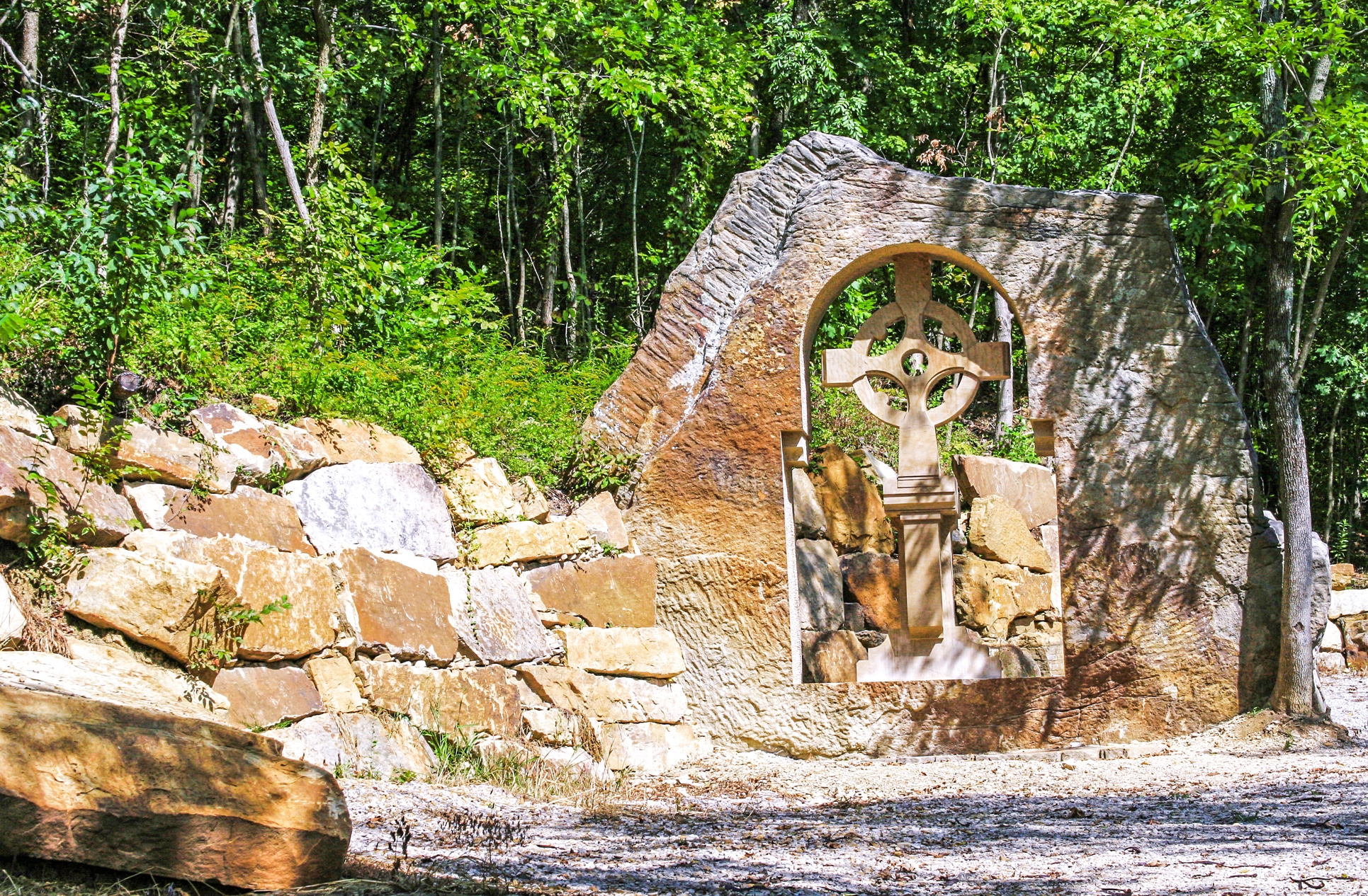 Celtic cross stone arch surrounded by lush greenery in a serene forest setting.