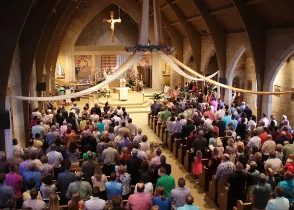 Crowd gathered for a church service in a beautifully decorated sanctuary.