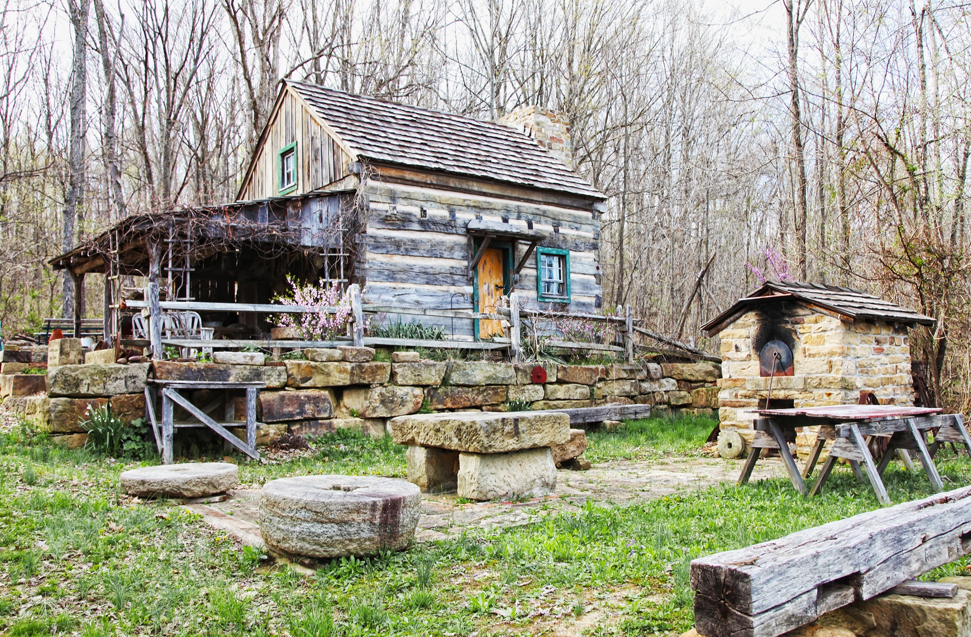 Rustic log cabin in the woods with stone landscaping and a charming backyard setting.