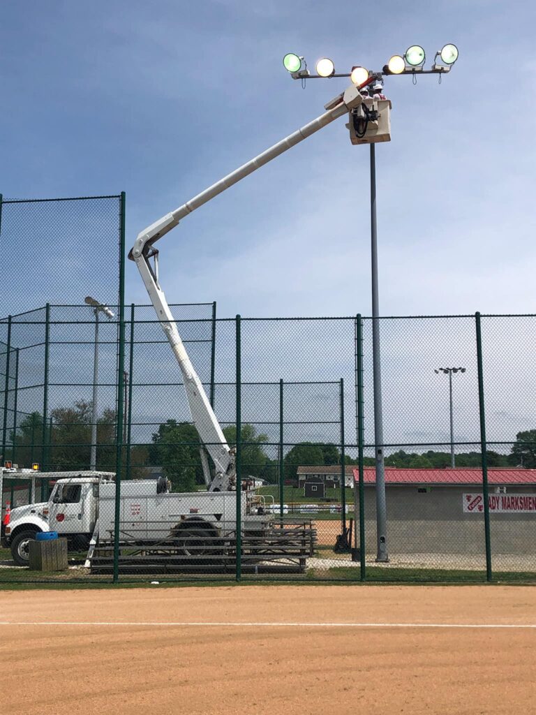 Maintenance crew working on baseball field lighting for optimal night games.