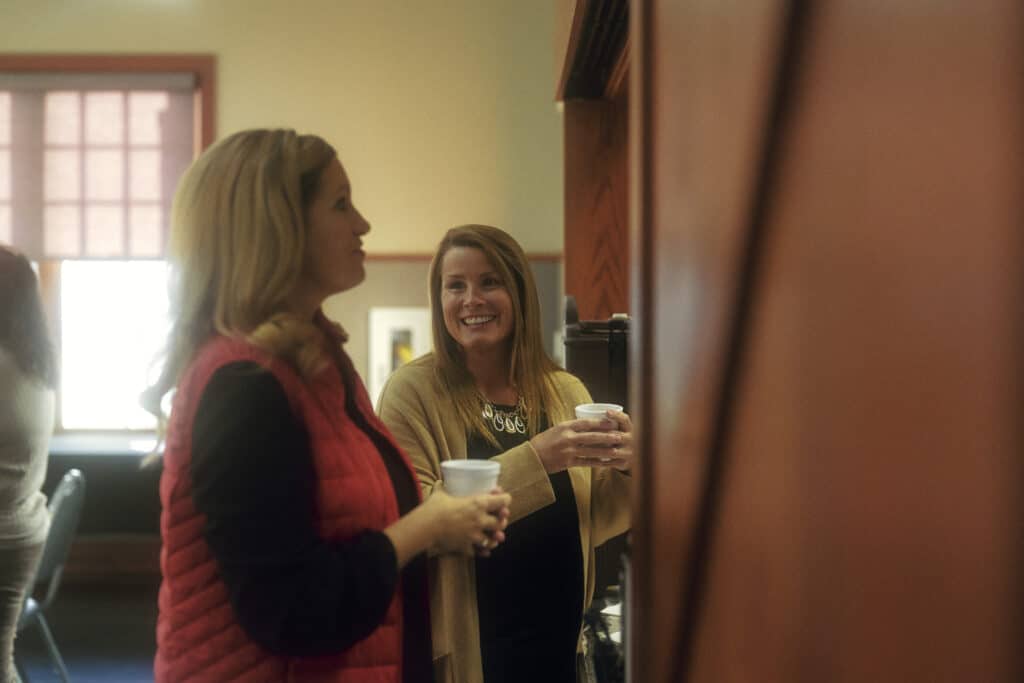 Women enjoying coffee and conversation during a break in a relaxed office setting.