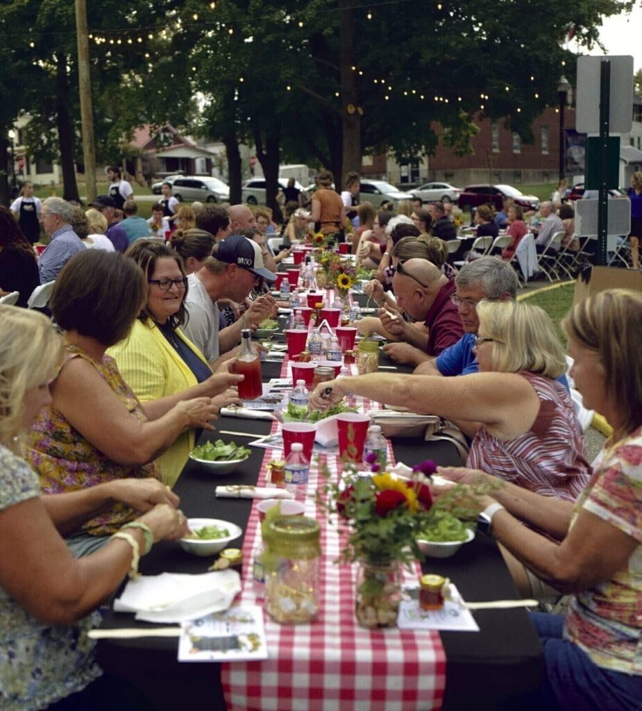 Community dinner event with friends enjoying food and conversation outdoors.