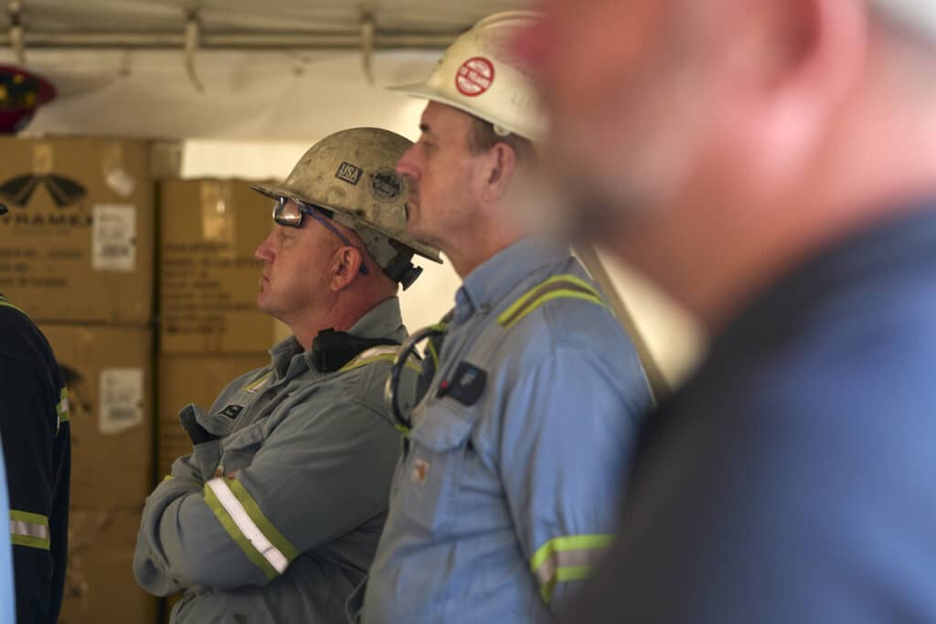 Construction workers engaged in a meeting, discussing safety and project updates.