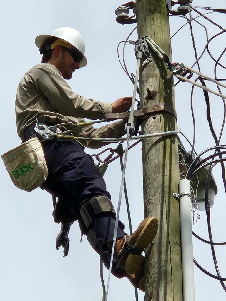 Electrician working on utility pole, connecting wires and ensuring safe electrical service.