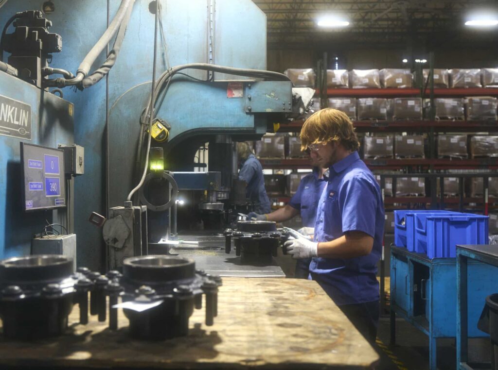 Workers operate machinery on an assembly line in a manufacturing factory.