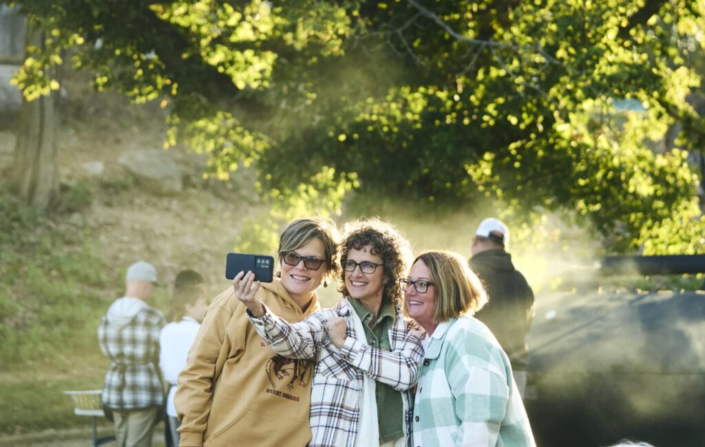 Friends taking a selfie together at sunset, capturing joyful moments outdoors.