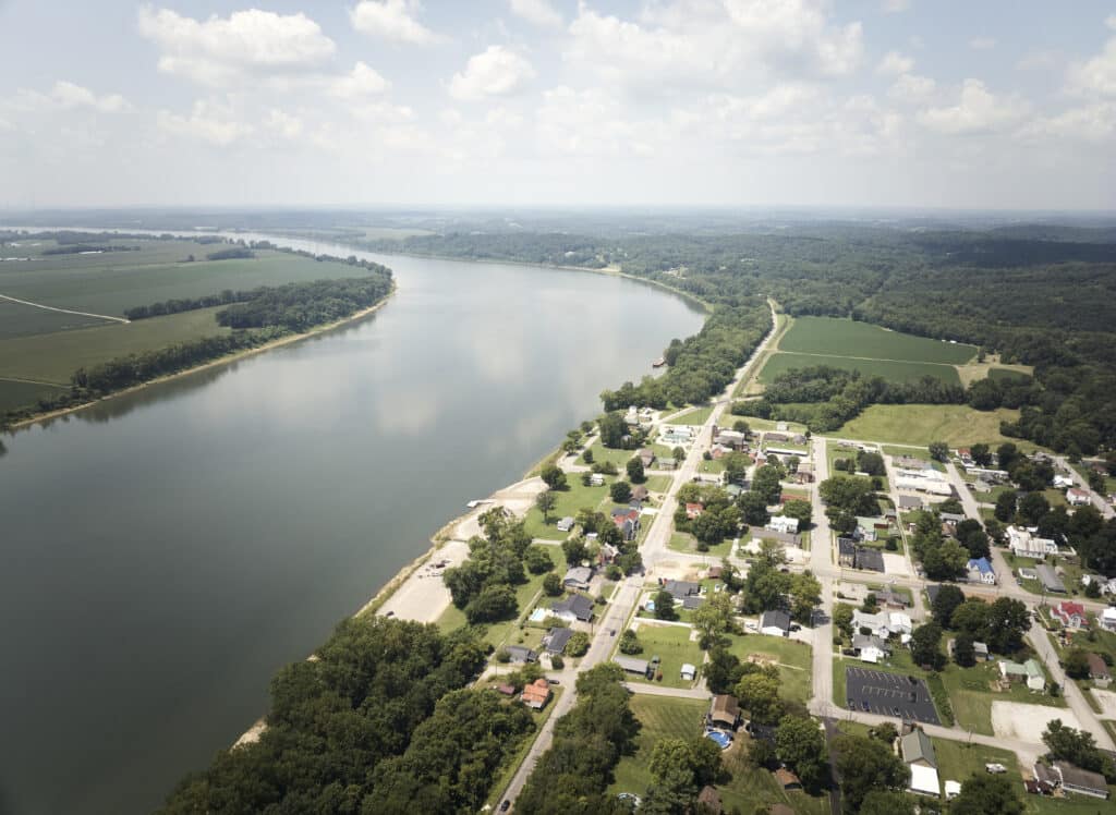 Aerial view of a river flowing past a charming riverside town and lush green fields.