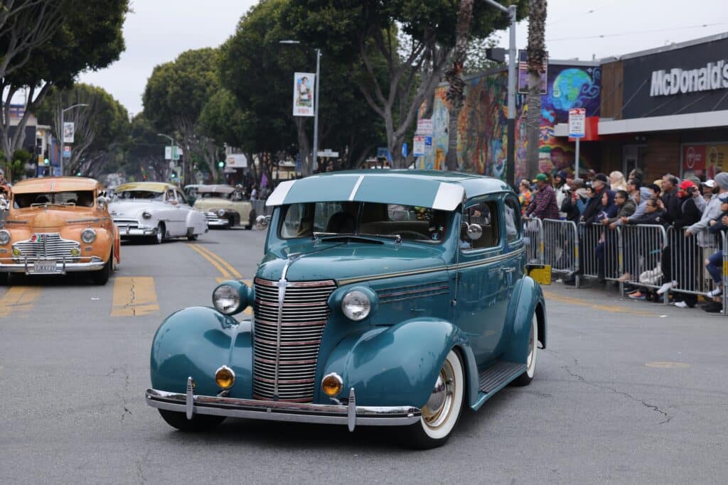 Classic vintage car parade showcasing exquisite automobiles on a lively street.