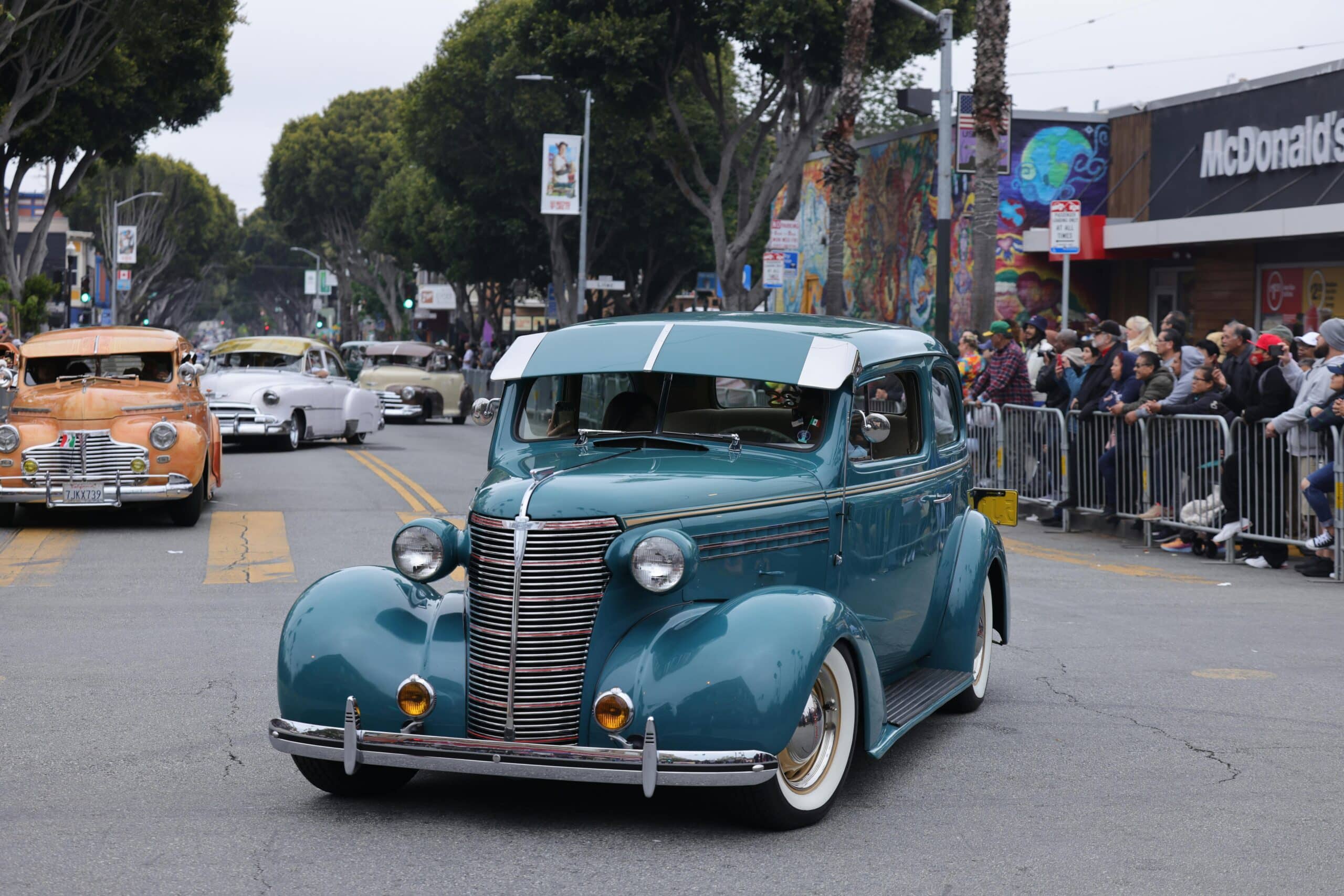 Classic vintage car parade showcasing exquisite automobiles on a lively street.