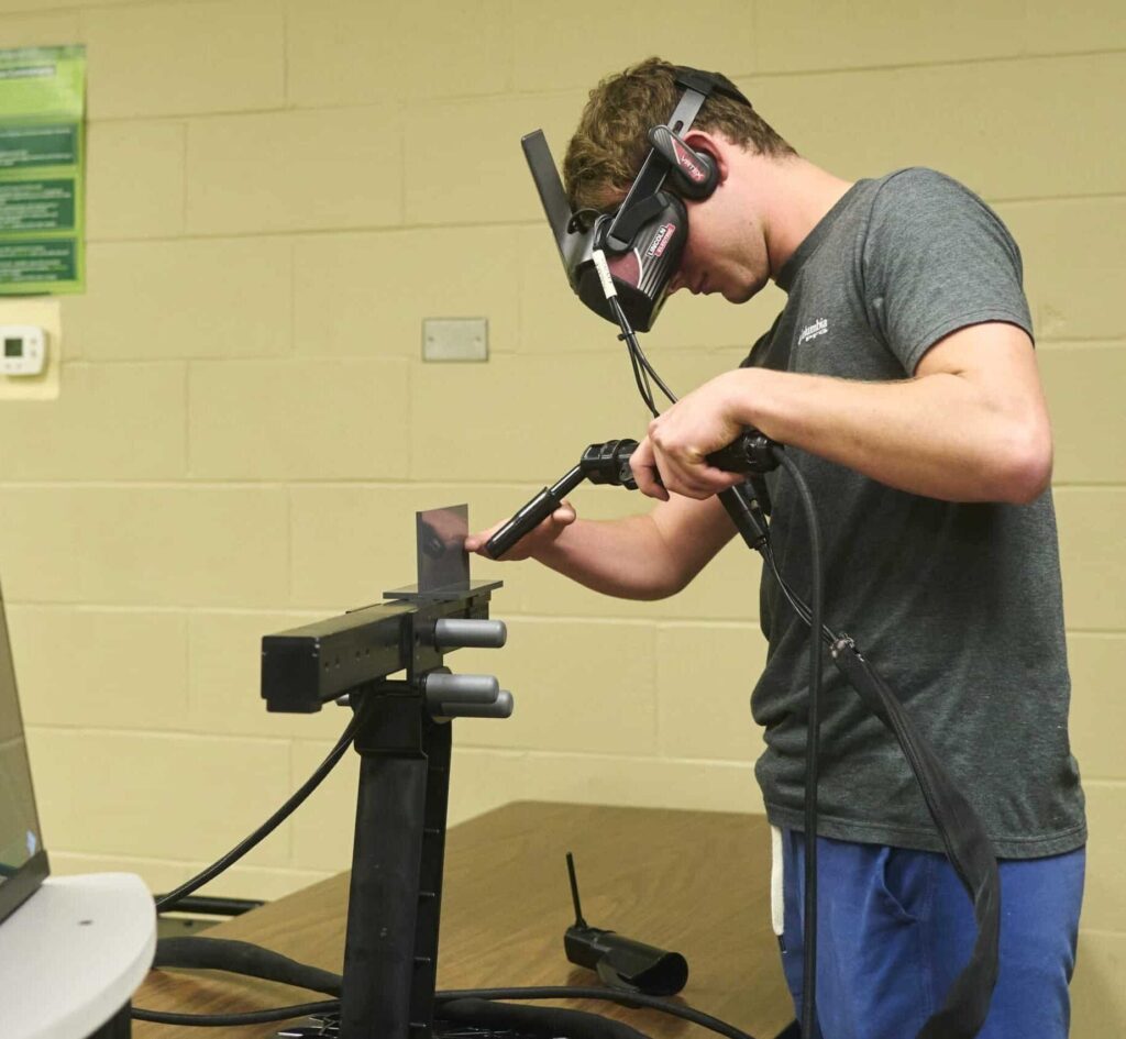Student practicing welding techniques using equipment in a training environment.