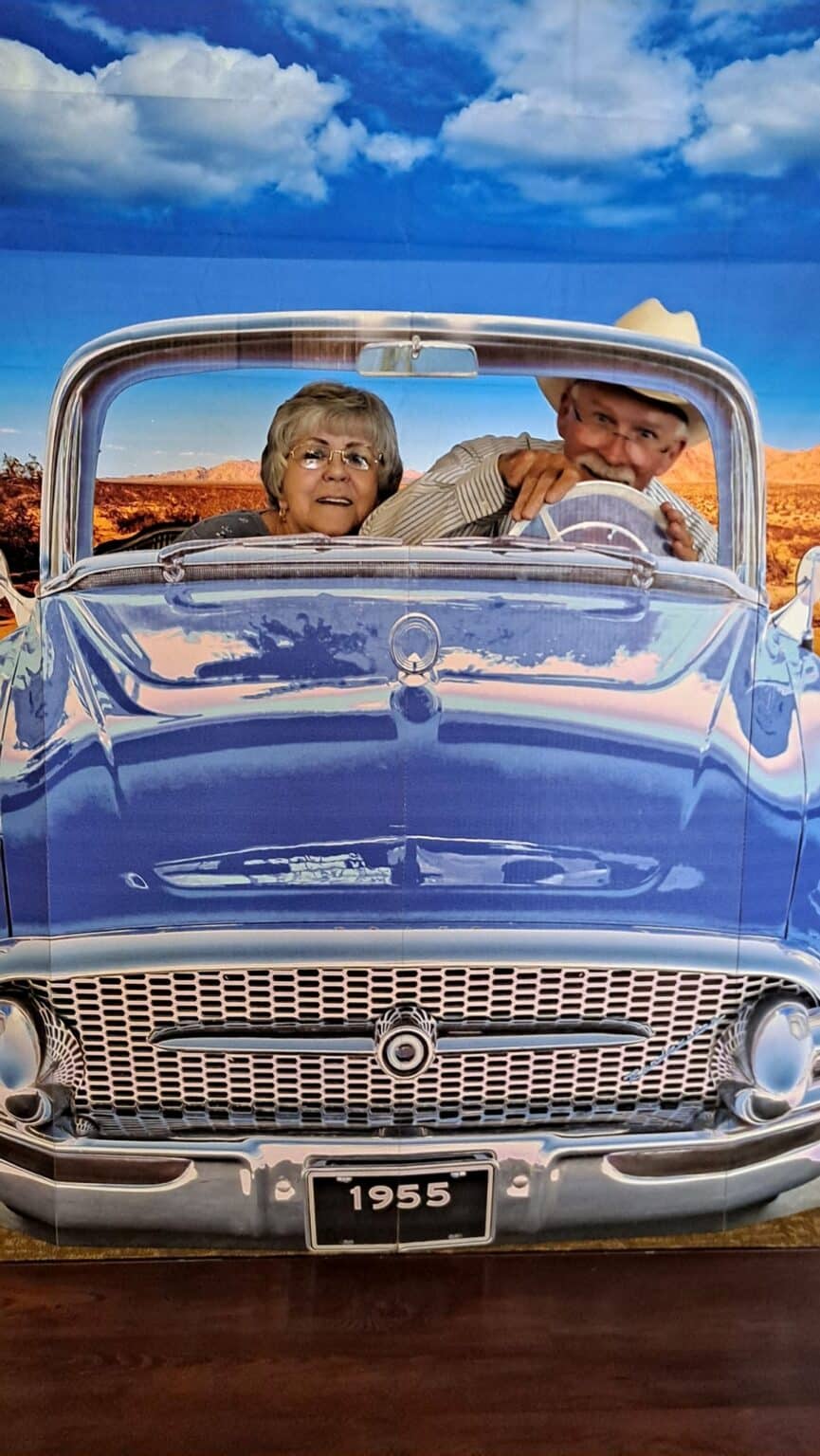 A couple enjoying a vintage car ride against a scenic backdrop.