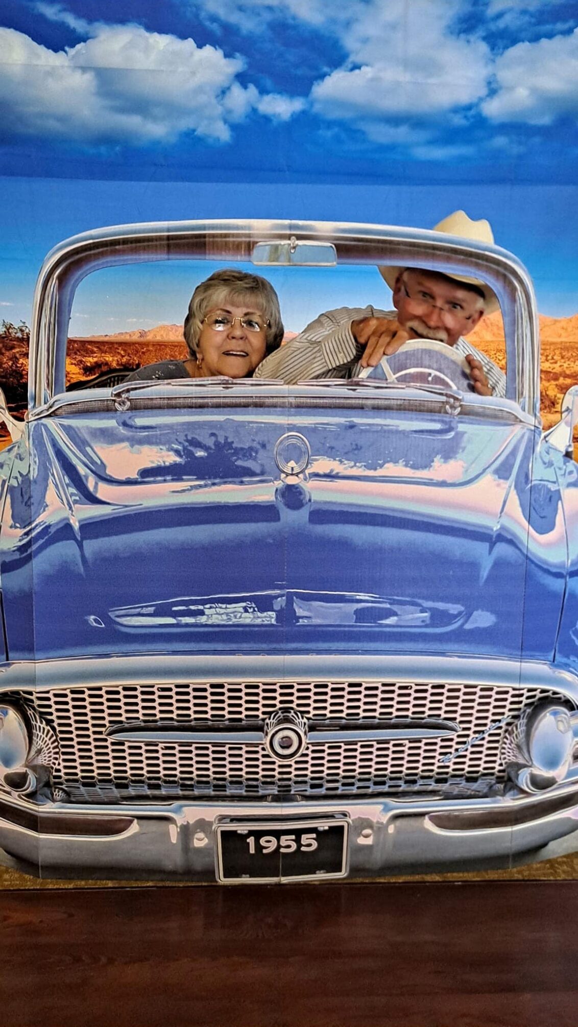 A couple enjoying a vintage car ride against a scenic backdrop.