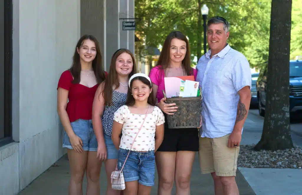 Family enjoying a summer day together, smiling outdoors with a picnic basket.