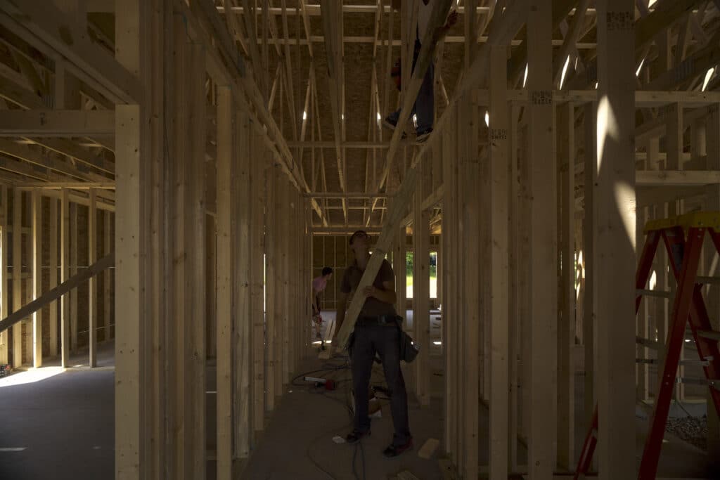 Construction workers framing a building with wooden beams at a construction site.