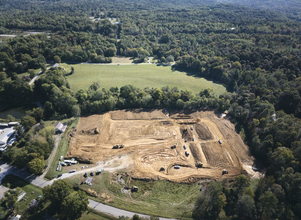 Aerial view of a construction site with heavy machinery and cleared land.