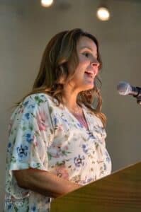 Speaker presenting at a professional event, engaging the audience with her message.